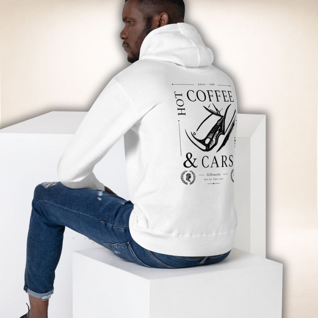 Sitzendes Model im weißen Siena Club Hoodie in Rückansicht mit schwarzem „Hot Coffee & Cars“-Motiv.
