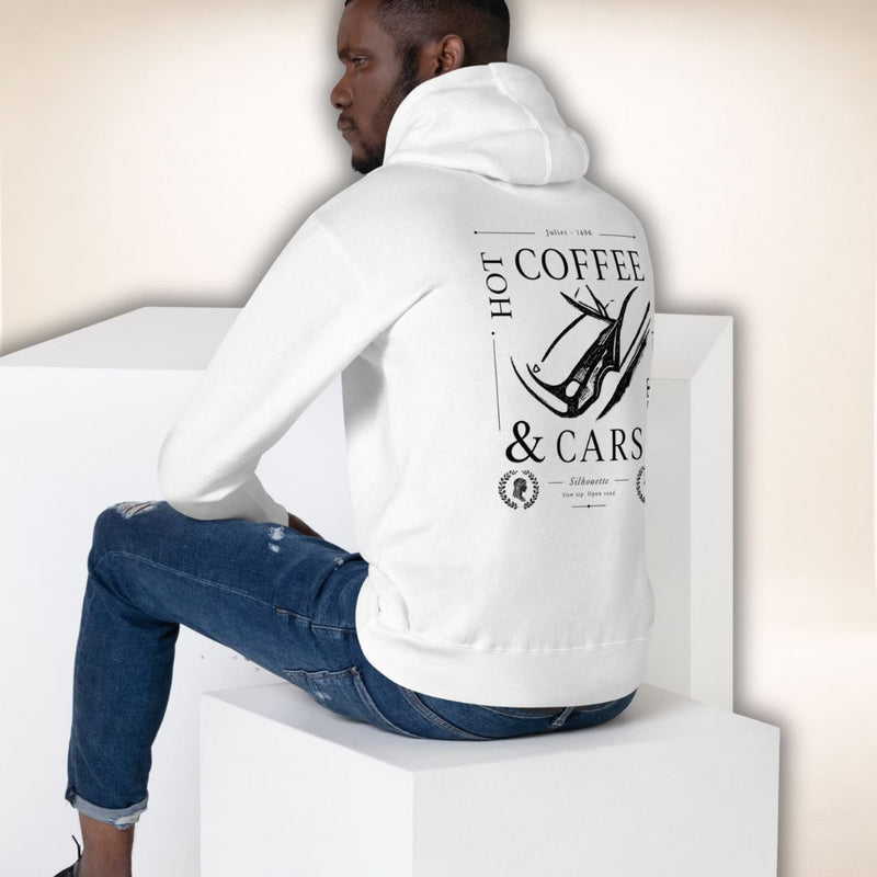 Sitzendes Model im weißen Siena Club Hoodie in Rückansicht mit schwarzem „Hot Coffee & Cars“-Motiv.
