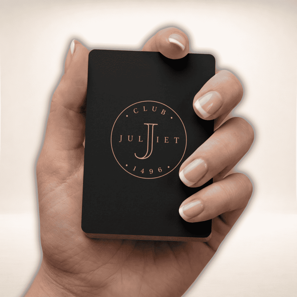 Hand hält das schwarze Club Juliet Pokerkarten-Set mit goldfarbenem Logo